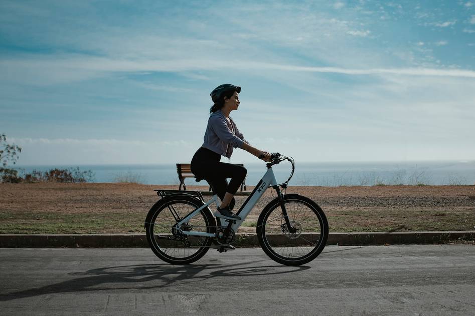 Blogger pedaling an ebike along a coastal trail at sunset