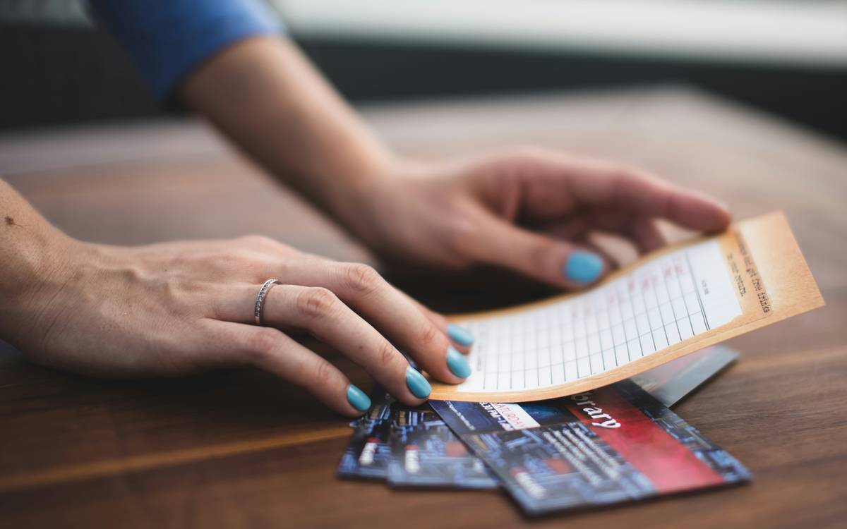 Hand holding a printed receipt next to a laptop showing a lower online price during a receipt price check